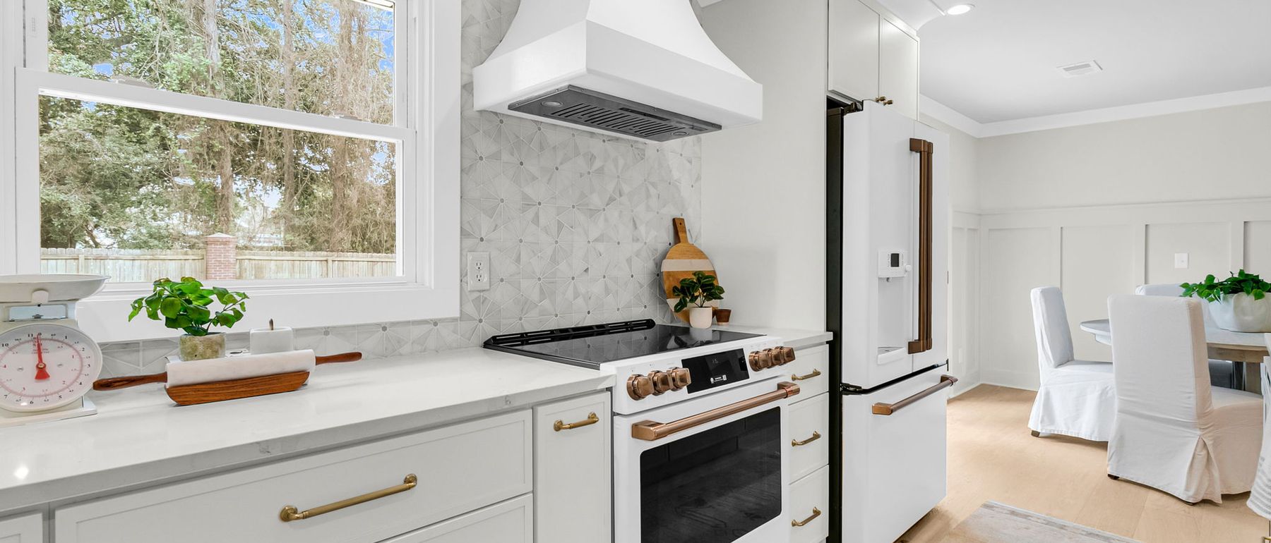 A bright renovated kitchen with marble counters and brass fittings