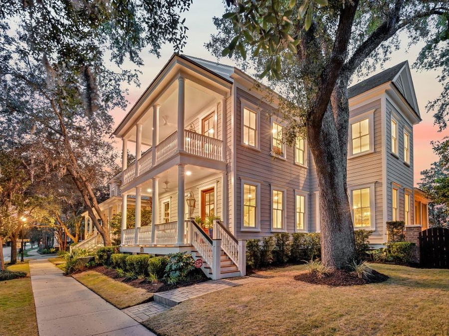 A Lowcountry home at dusk beneath a live oak, lit from within